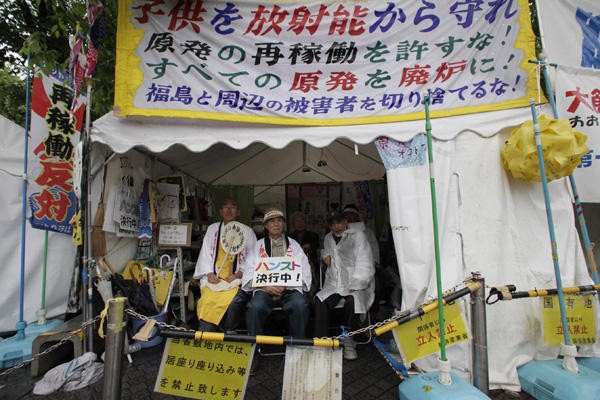 Các nhà hoạt động chống năng lượng nguyên tử Taro Fuchigami (phải), Taichi Masakiyo (giữa) và một tu sĩ Phật giáo đang tuyệt thực trong một căn lều trước Bộ Kinh tế, Thương mại và Công nghiệp Nhật Bản. Hình: Shizuo Kambayashi/AP