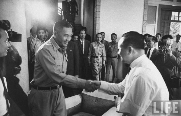 23 tháng Ba 1964, Tướng Minh bắt tay bác sĩ Lê Khắc Quyến, một thành viên trong Thượng Hội Đồng Quốc Gia. 