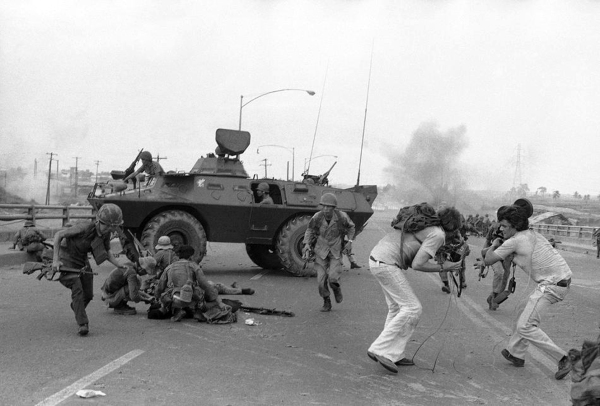 Quân lính Nam Việt Nam và nhóm phóng viên truyền hình Phương Tây tìm chỗ trú ẩn trước đạn pháo của người Bắc Việt ở cầu Tân Cảng, Sài Gòn, 28 tháng Tư 1975. Hình: AP Photo/Hoanh 