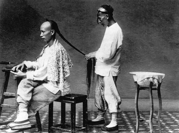 Một đầy tớ thắt bím cho chủ. Theo lệnh của triểu nhà Thanh, tất cả đàn ông Trung Quốc đều phải để bím tóc. Ảnh: GEO EPOCHE