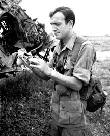 Peter Arnett đứng cạnh một chiếc A 1 Skyraider đã cháy rụi vào ngày 12 tháng Mười 1965 ở gần Biên Hòa