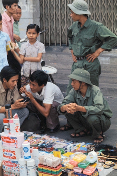 Sài Gòn, 29 tháng Năm: Những người bán hàng chợ đen vẫn kinh doanh như bình thường các món hàng trộm ra từ PX. Nhưng người mua bây giờ là những người lính của Chính phủ Lâm thời.